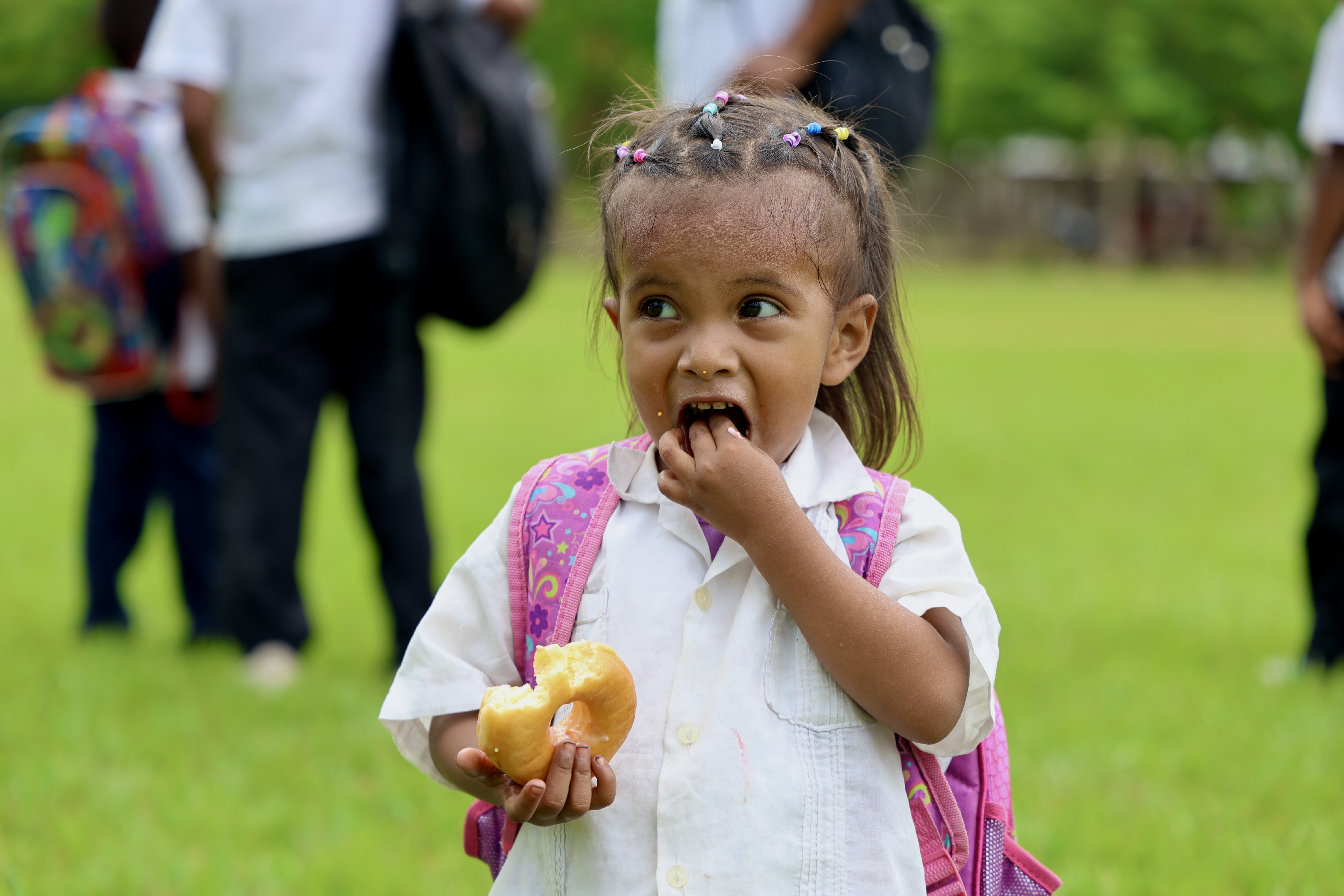 Young girl with backpack eating